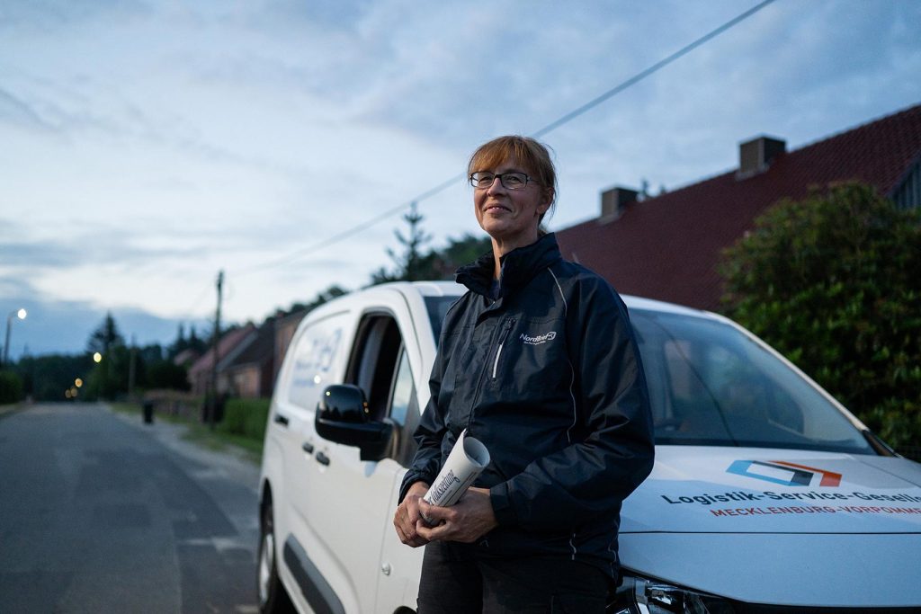 glückliche Frau vor einem Logistik-Auto